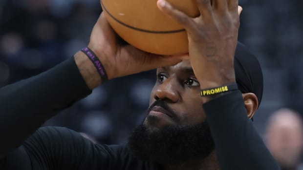 LeBron James con camiseta negra de manga larga sostiene balón entre sus manos.